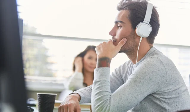Person wearing headphones at a desk listening to an audio program
