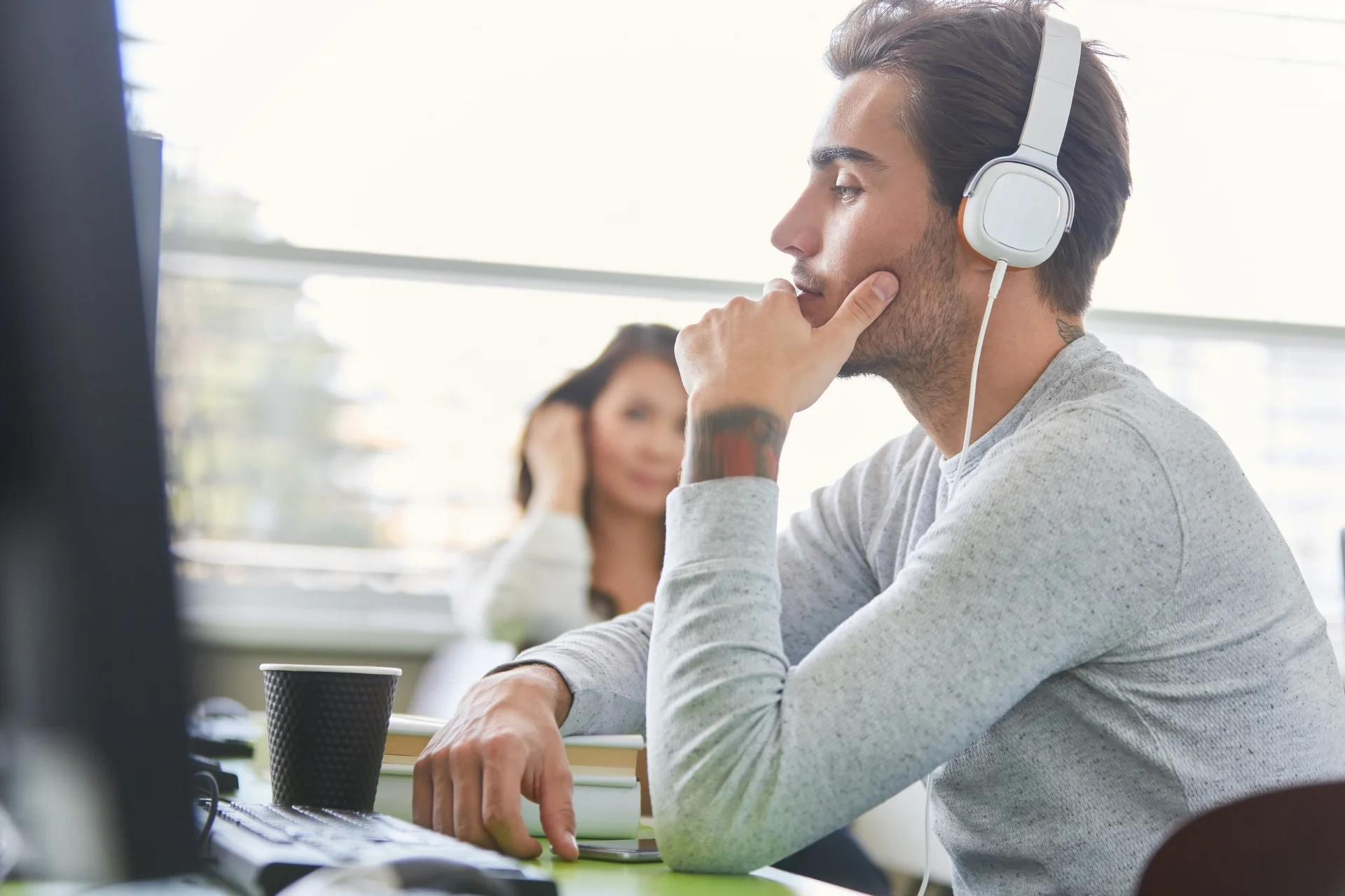 Man sitting at computer with headphones listening to nervous system burnout recovery tools mobile version